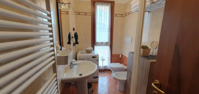 Salle de bain avec lavabo, lave-linge et fenêtre